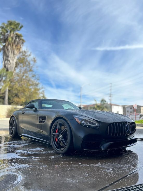 A man is washing a car in a car wash.