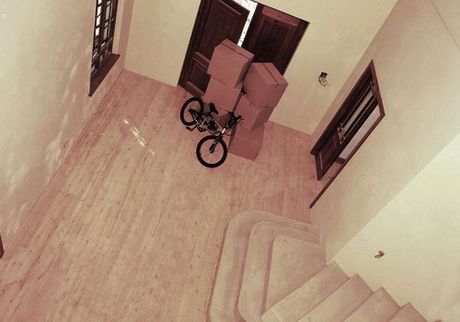 A bike and some boxes on a wooden hallway floor, seen from the landing