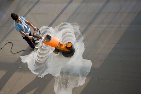 Aerial view of a lady using an industrial floor cleaner