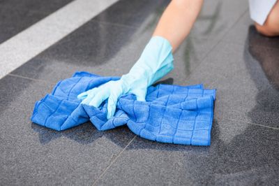 A marble floor being wiped with a blue cloth