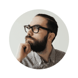 A man with a beard and glasses is thinking about something.