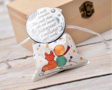 Una statuetta raffigurante un bambino con un cappello da coniglio, che tiene in mano una carota, davanti a una borsa di tulle bianco legata con un nastro.