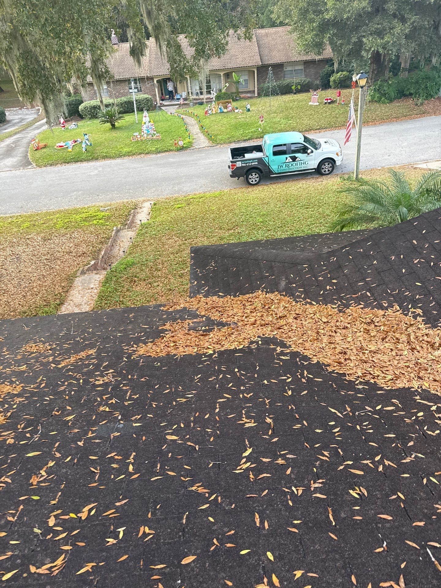 View from a dark roof, with scattered leaves. A truck parked in a residential street.
