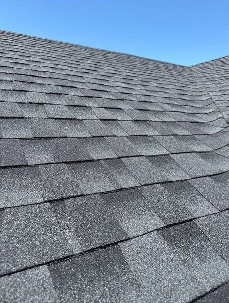 Gray asphalt shingle roof against a clear blue sky.