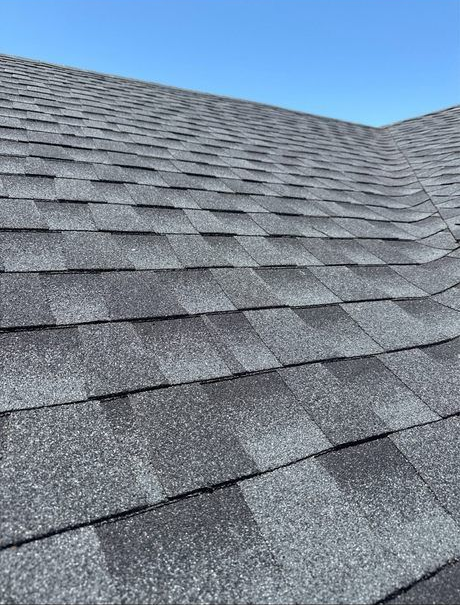 Gray asphalt shingle roof against a clear blue sky.