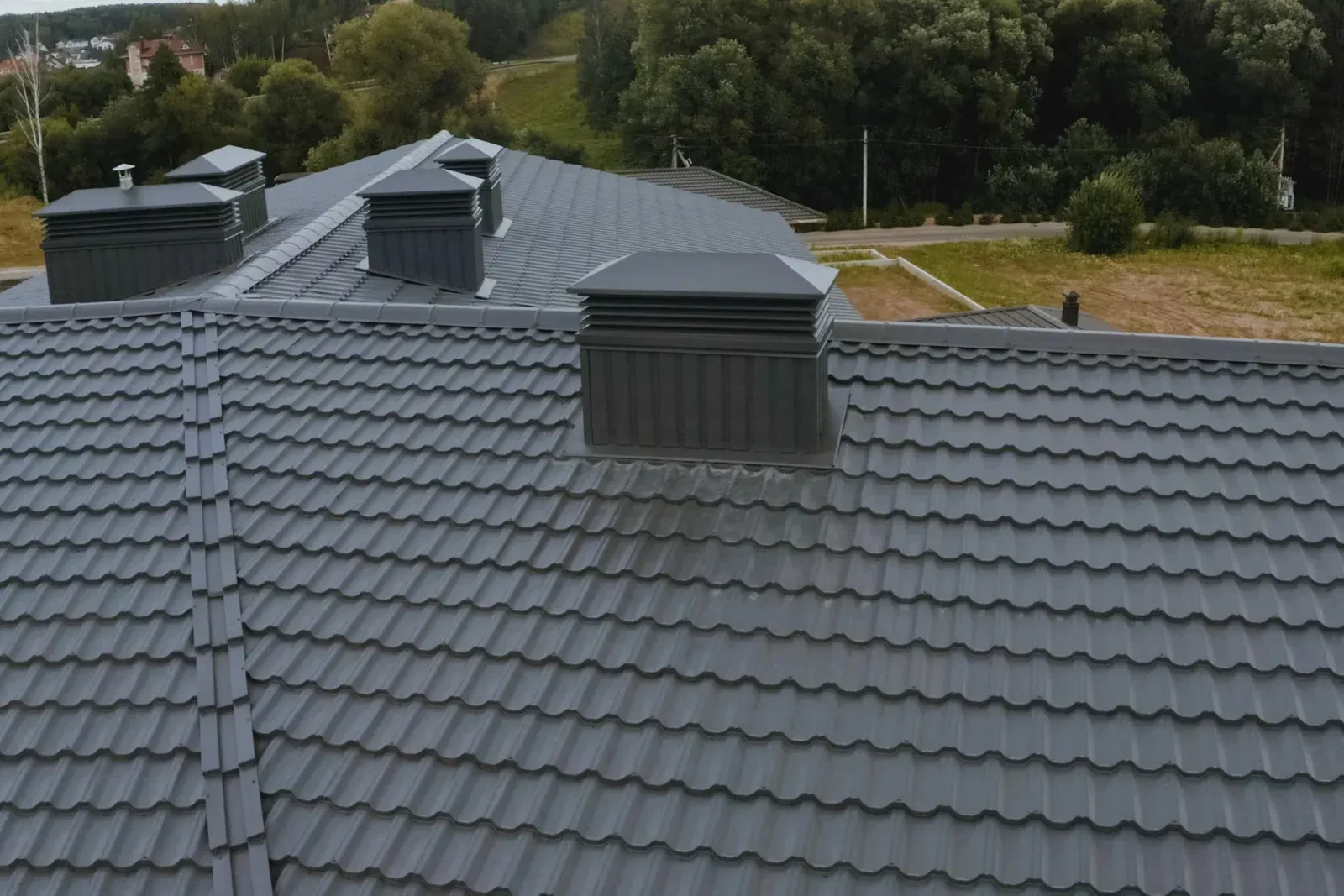 Gray metal roof with multiple dark rectangular chimney vents.