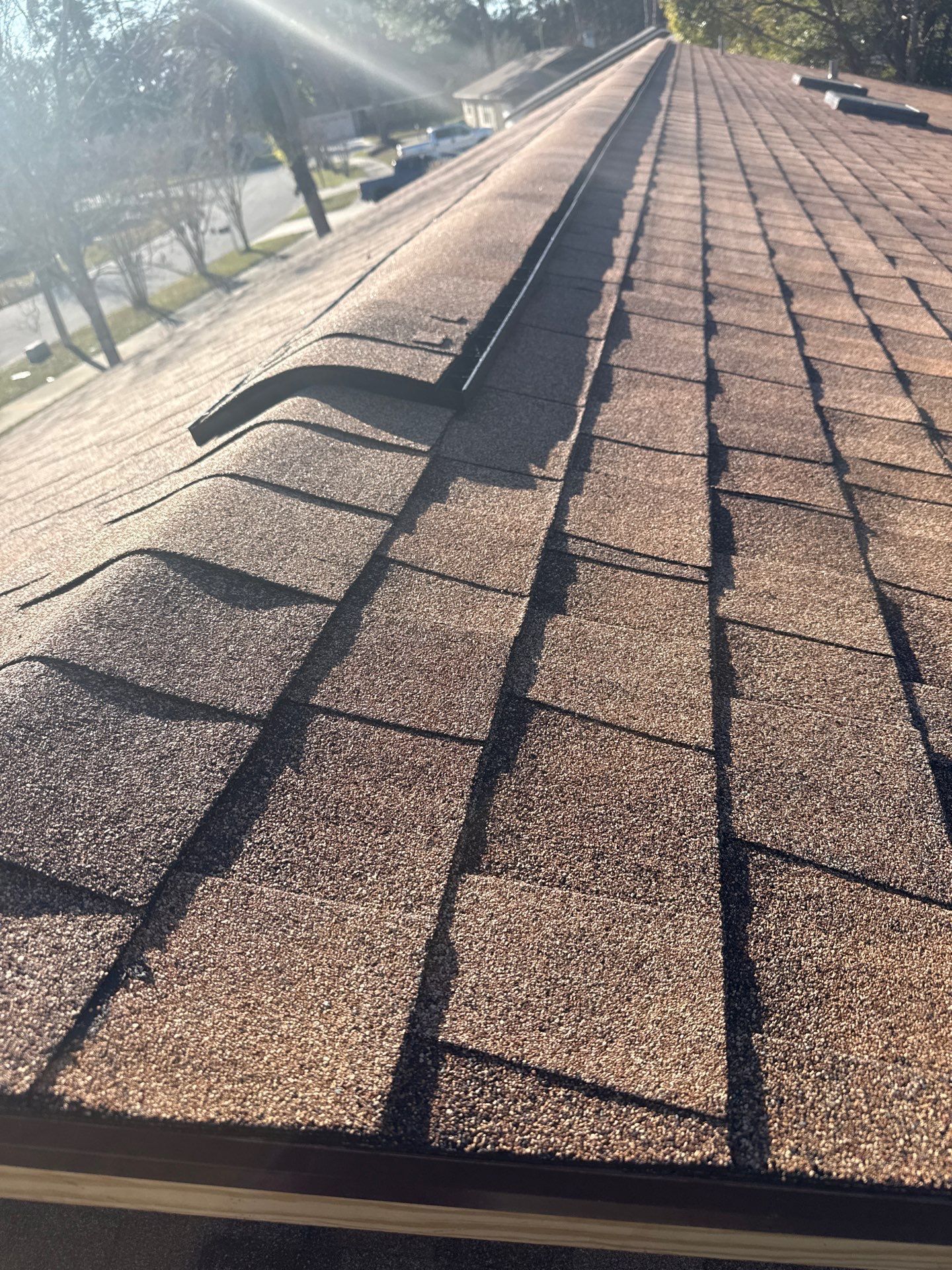 Close-up of a brown shingle roof on a sunny day.