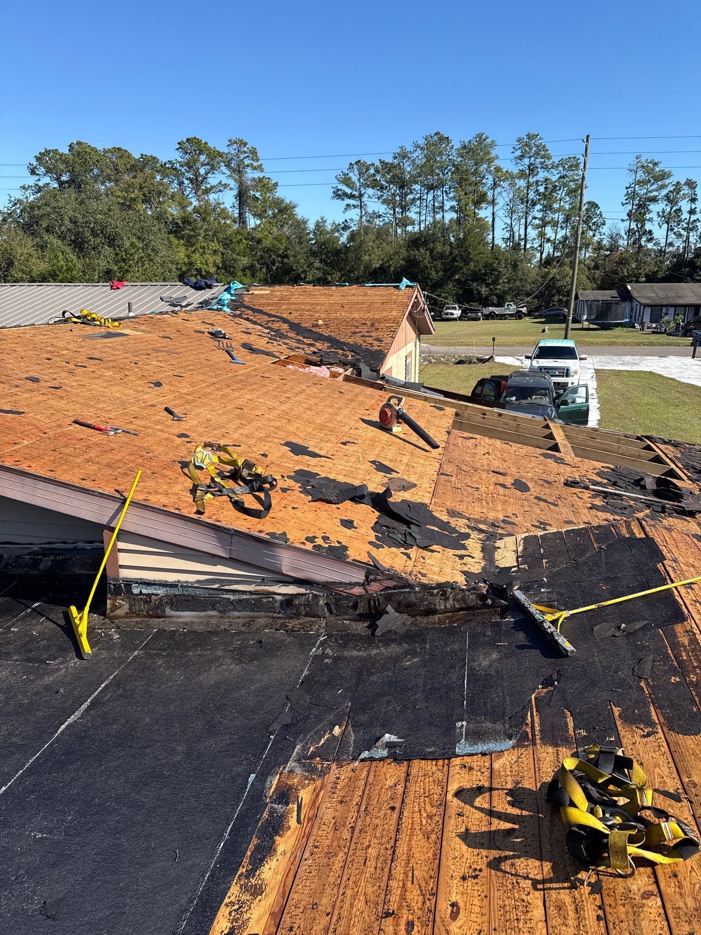 Roof partially torn off during repair, with exposed wood and construction equipment.