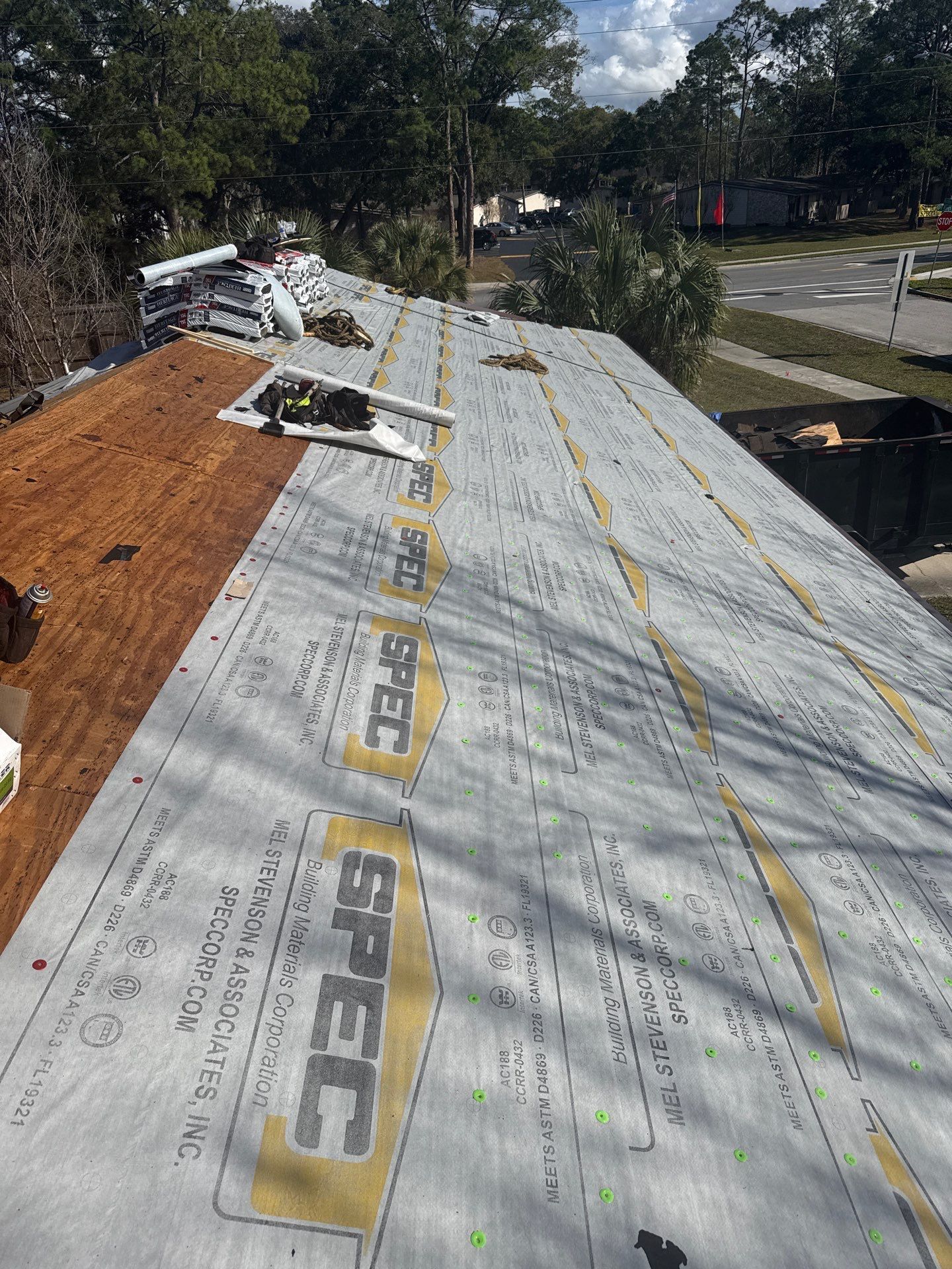 Roof under construction; gray underlayment installed, wooden boards exposed on left.
