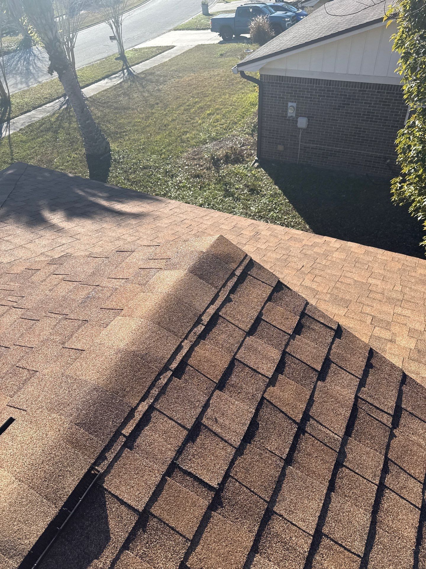 Brown shingle roof with a ridge, viewed from above, and part of a house and yard.