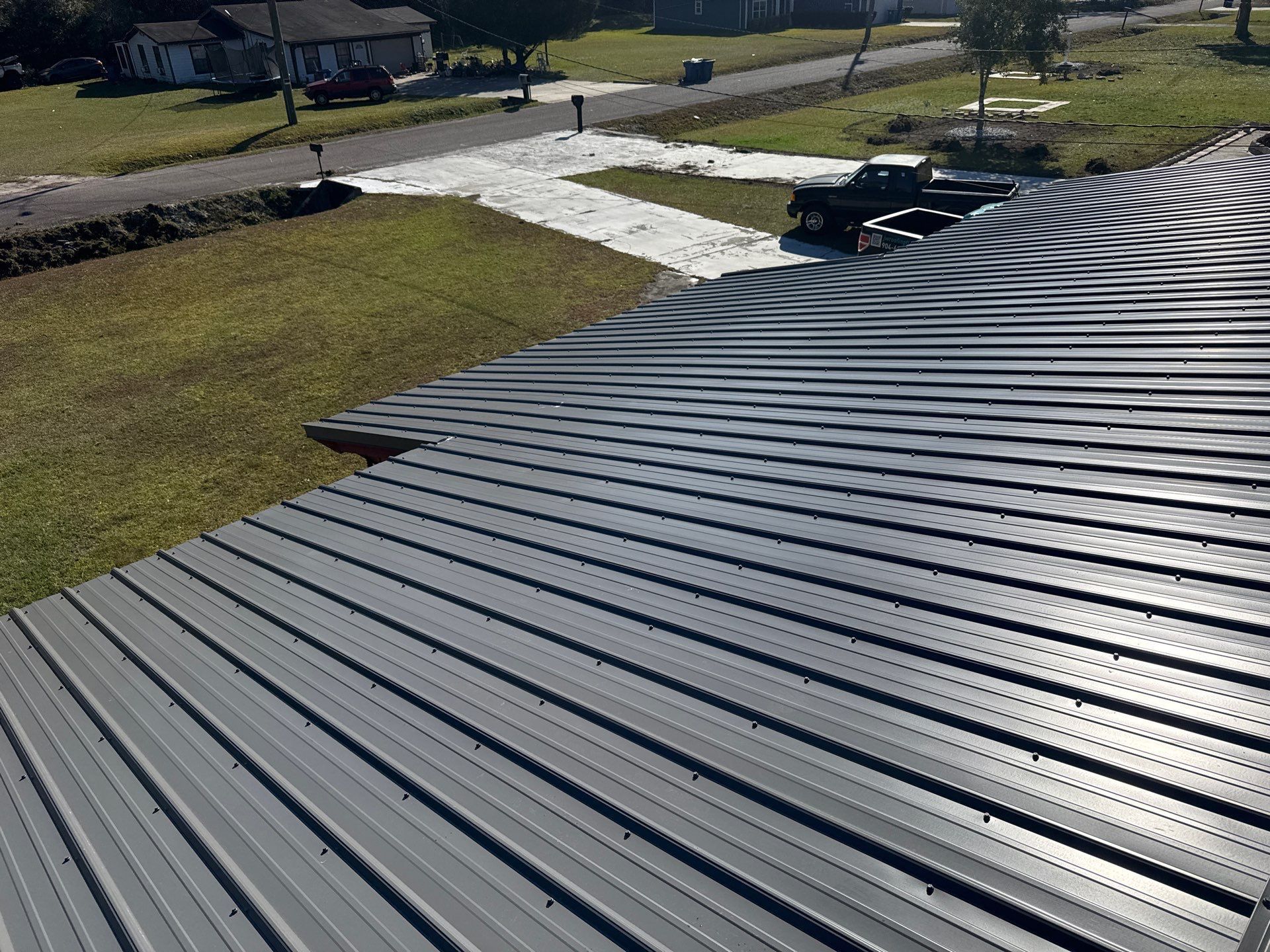 Gray metal roof with ribbed texture, overlooking a grassy yard and street.