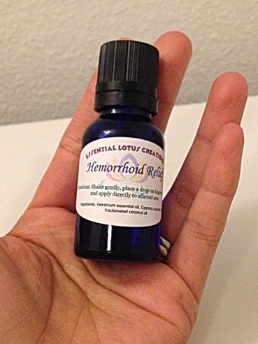 Hand holding a small purple bottle labeled “Hemorrhoid Relief” with a black cap.