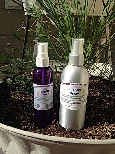 Two spray bottles of dog ear solution, one purple and one silver, on a soil-filled planter with plants.