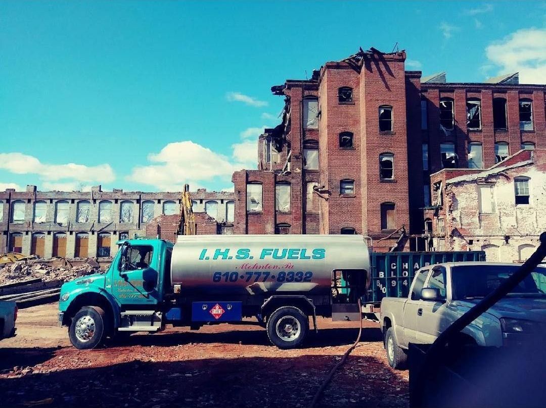 A l.h. & fuels truck is parked in front of an abandoned building