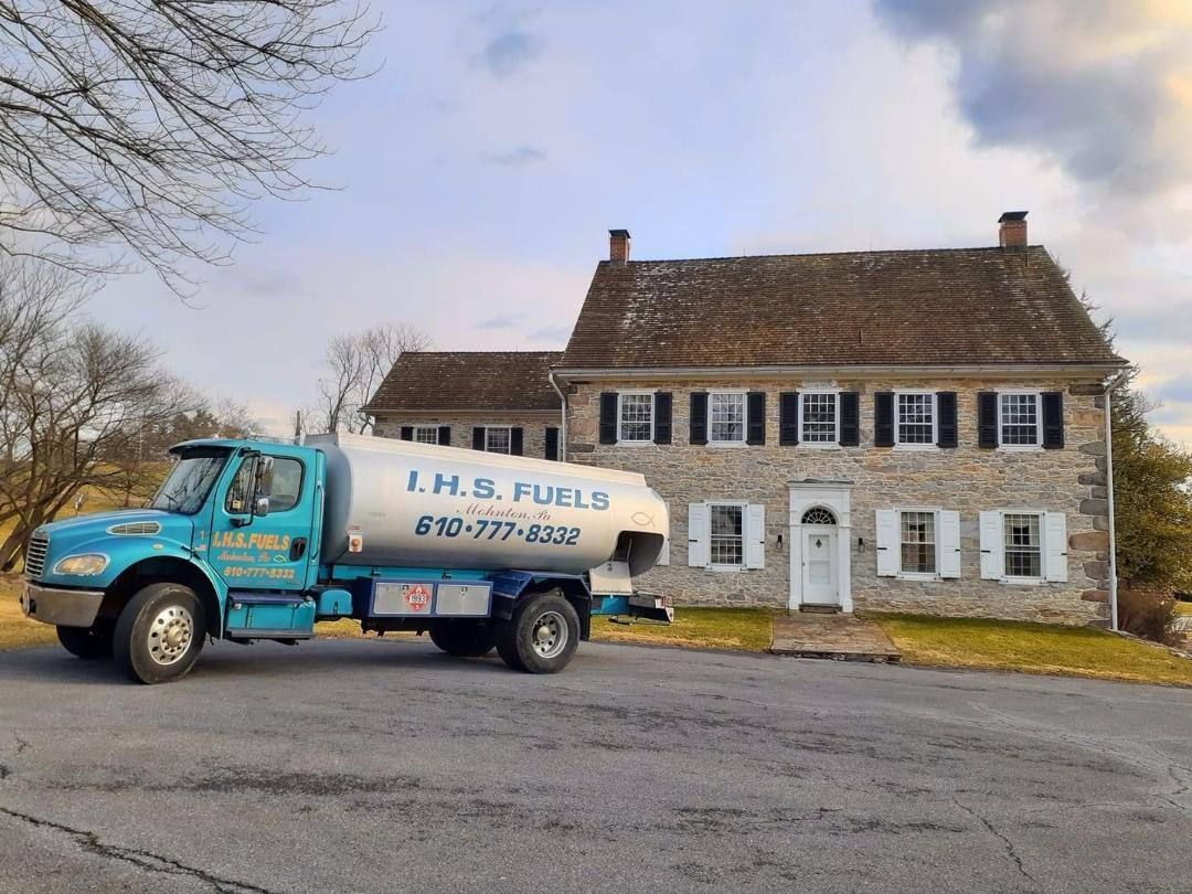 A blue truck is parked in front of a stone house.