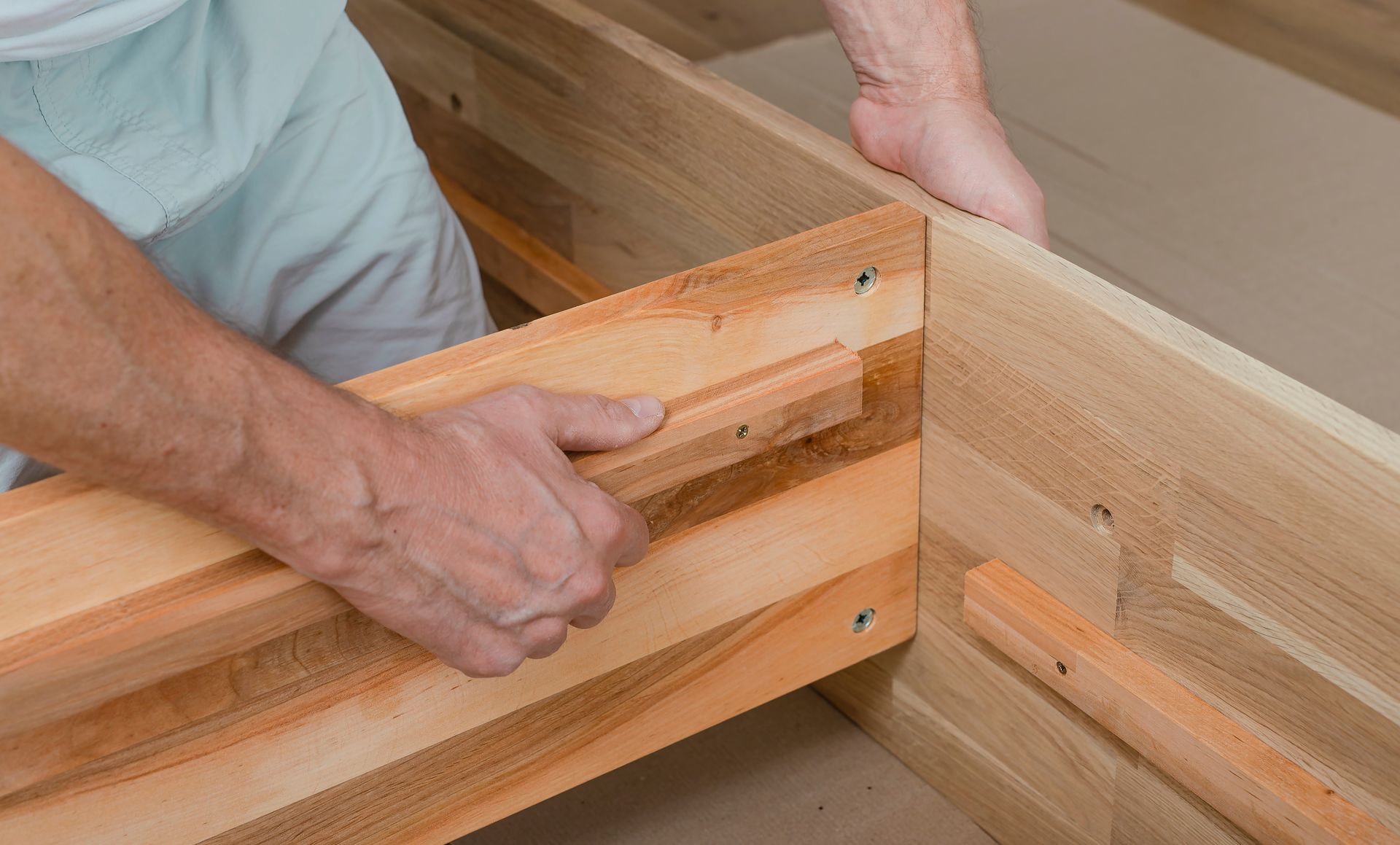 Hands assembling a wooden bed frame with a clamp in a workshop Hands assembling a wooden bed frame with a clamp in a workshop