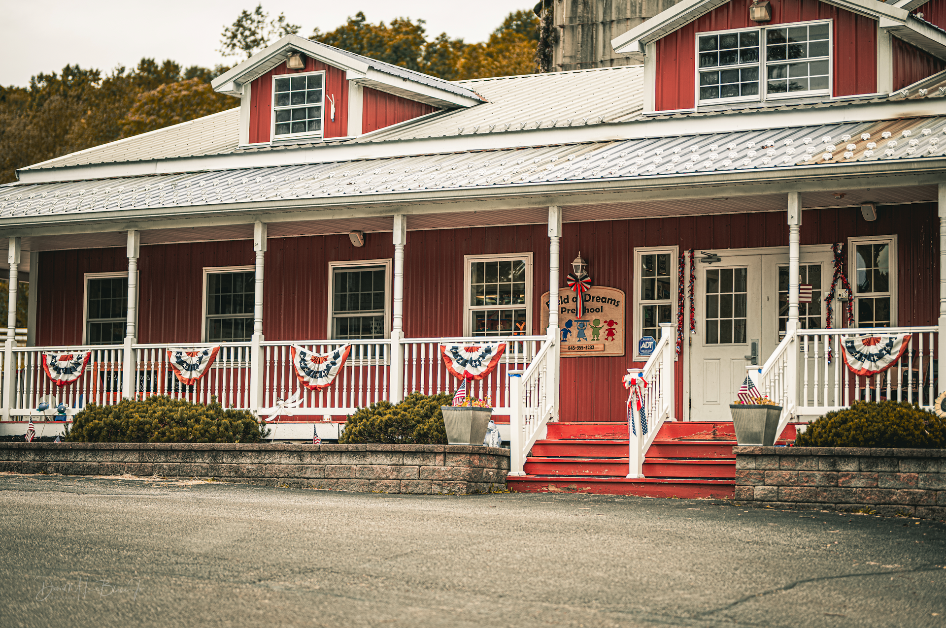 Red and white wooden building with a porch, American flags and decorations.