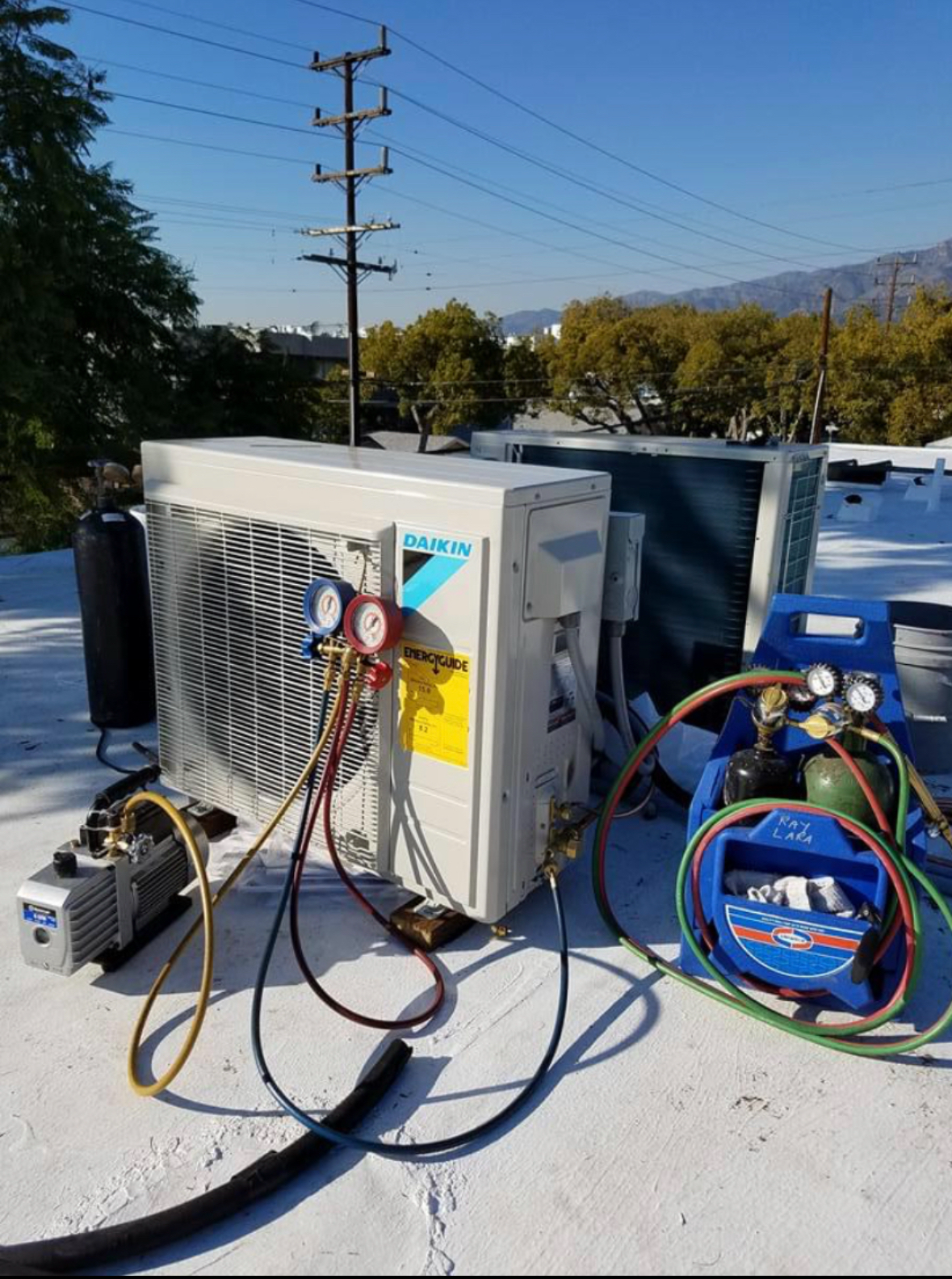 Air conditioning units with toolbox and gloves in backyard.