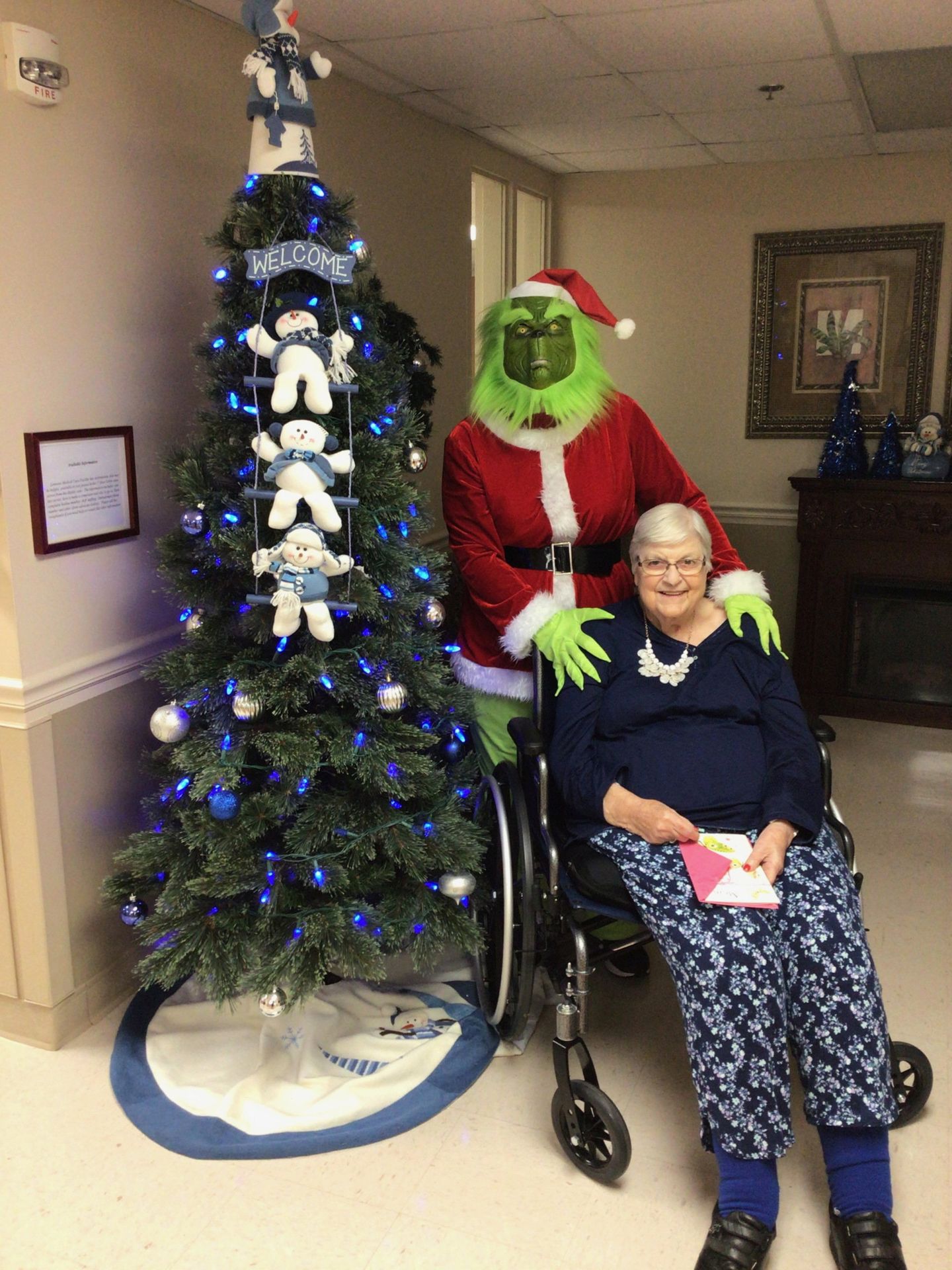 Elder posing with the Grinch by a Christmas tree at Lenawee Medical Care Facility in Adrian, MI