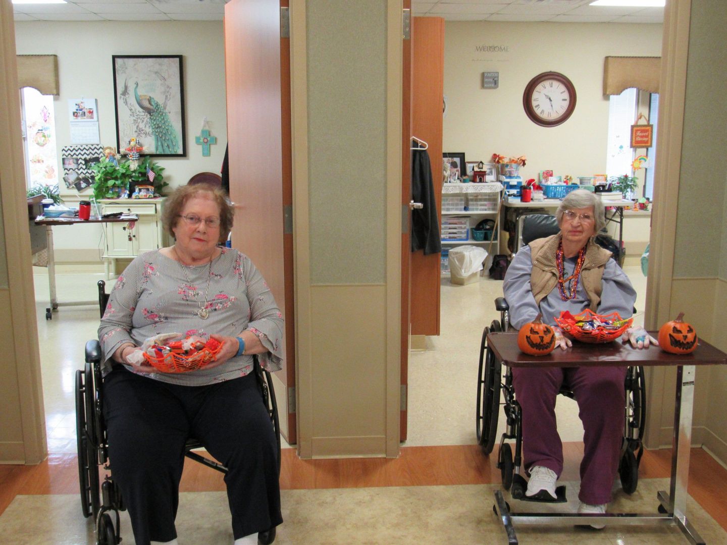Two Elders sitting outside their rooms handing out Halloween candy at Lenawee Medical Care Facility in Adrian, MI