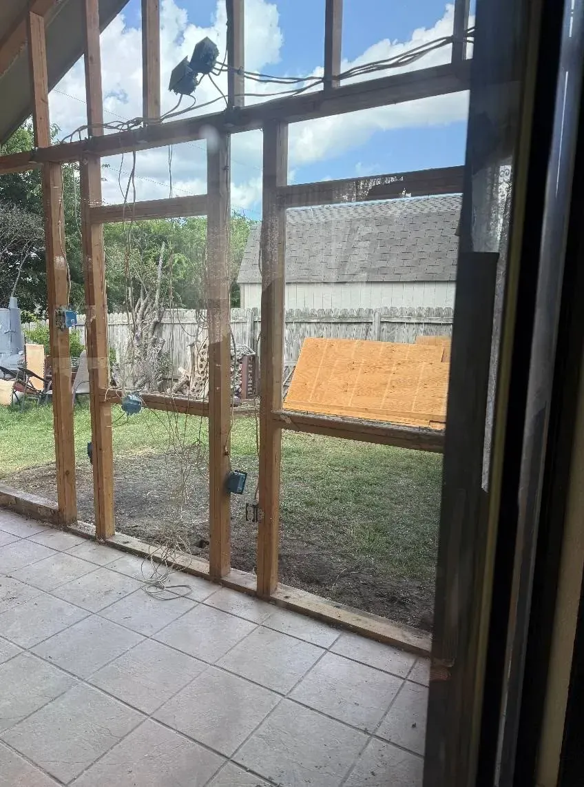 Wooden frame construction of an outdoor structure on a tiled patio with a grassy backyard visible.