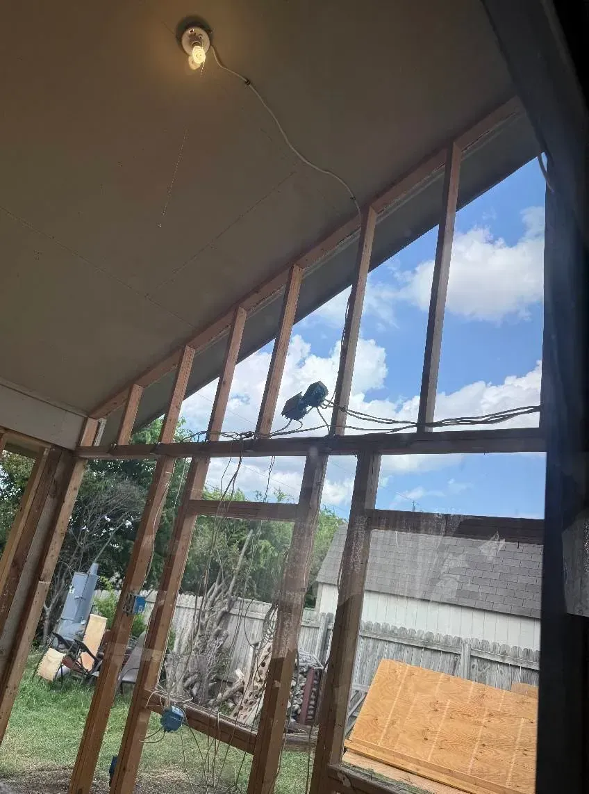 Construction site: wooden frame with a partially built roof, open to a bright blue sky.