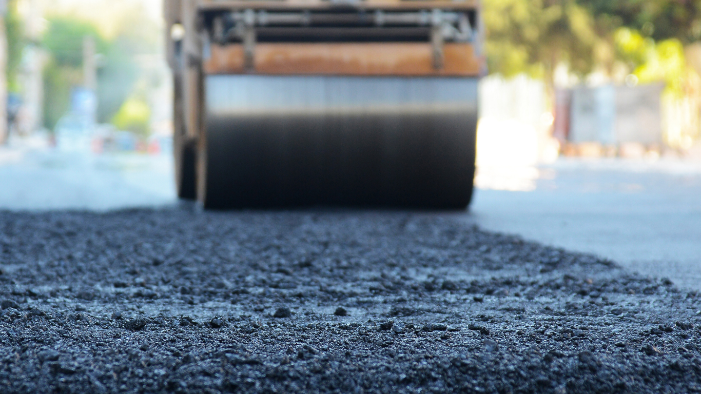 Road roller compacting fresh asphalt on a street.
