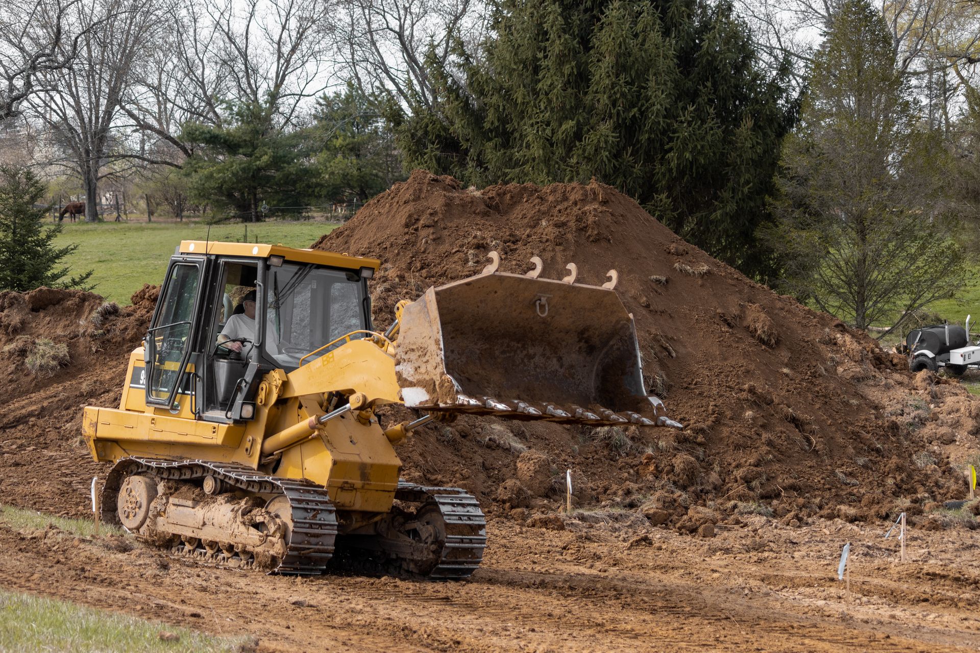 A bulldozer is moving dirt on a dirt road.