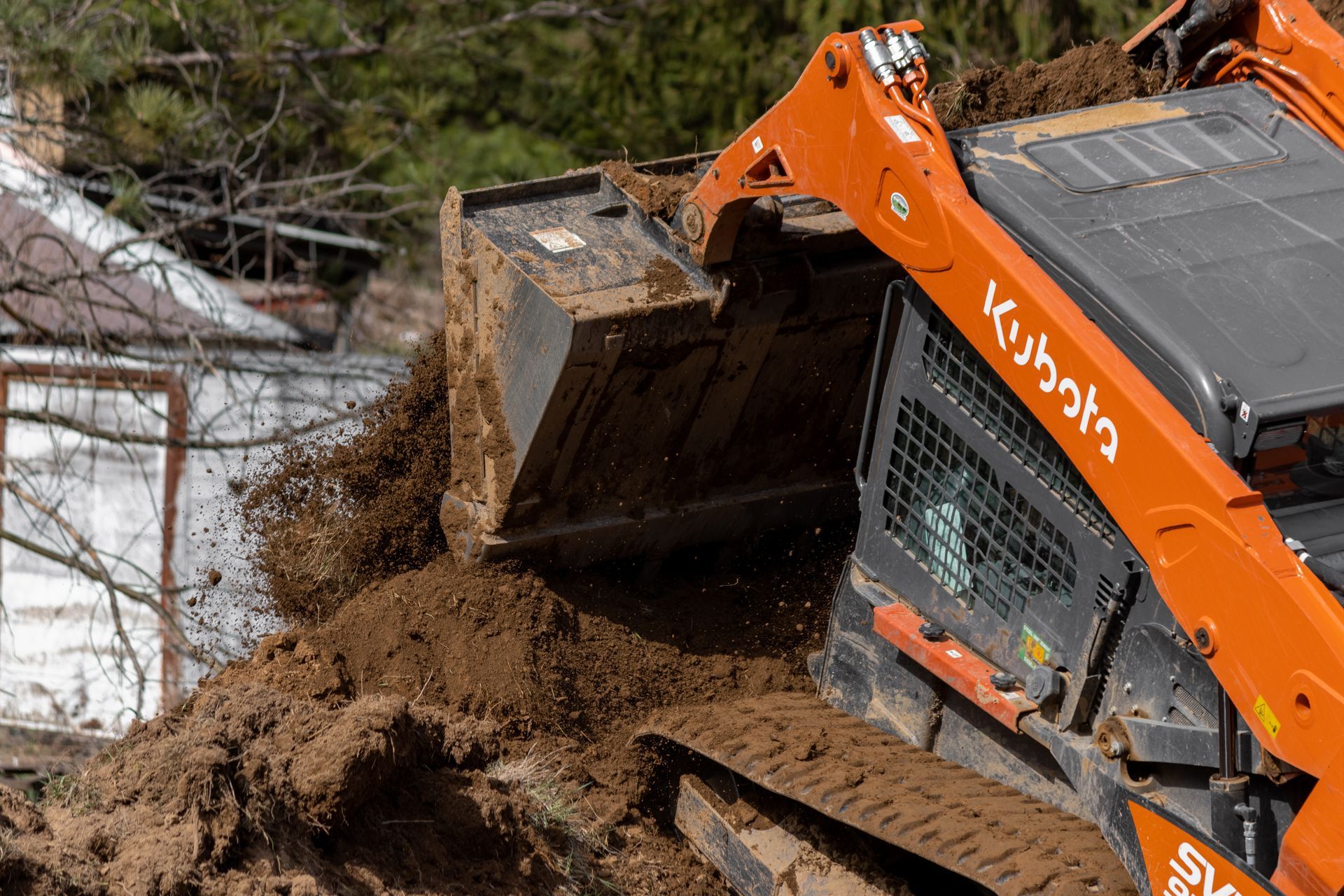 A kubota bulldozer is loading dirt into a bucket.