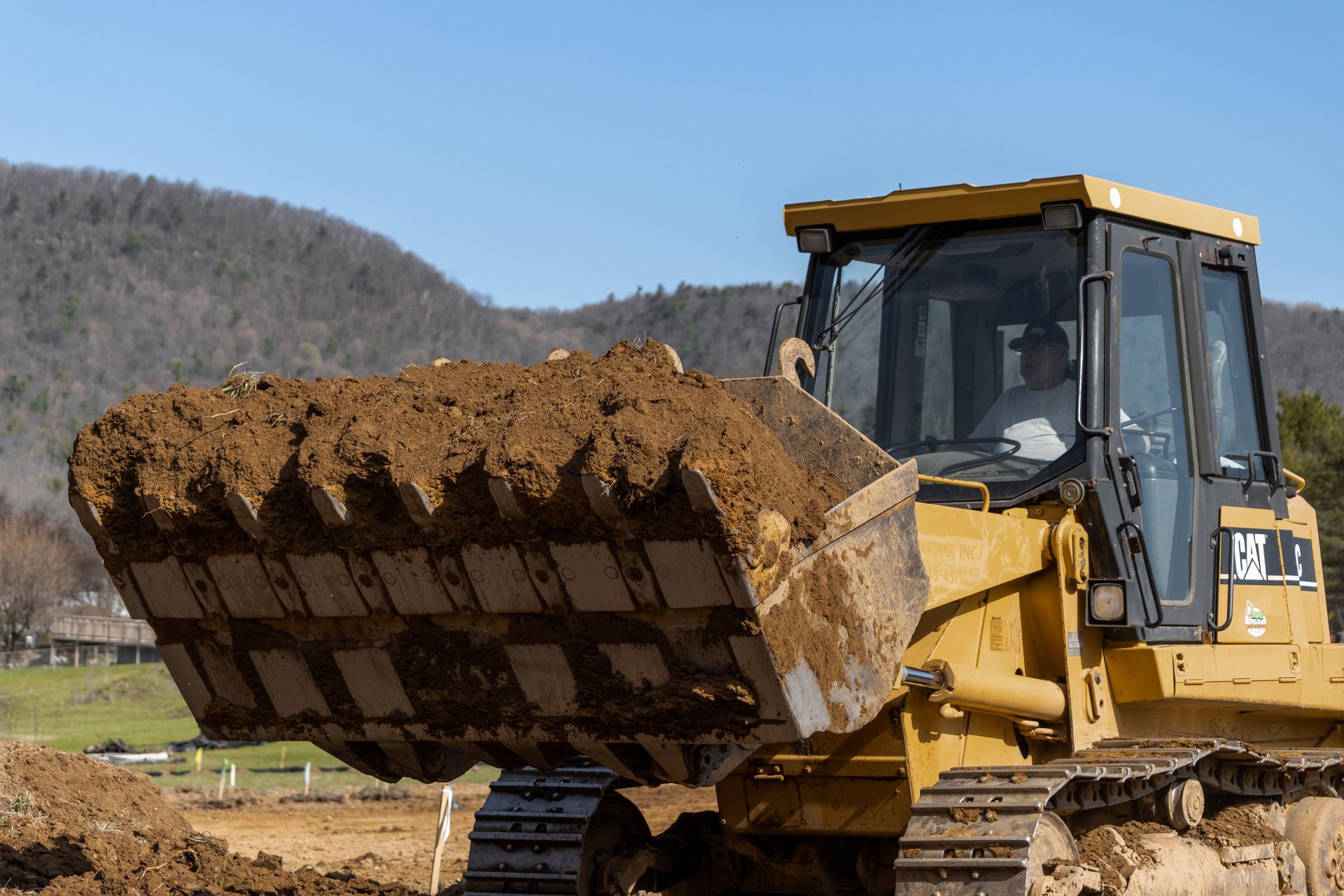 A bulldozer is loading dirt into a dump truck.