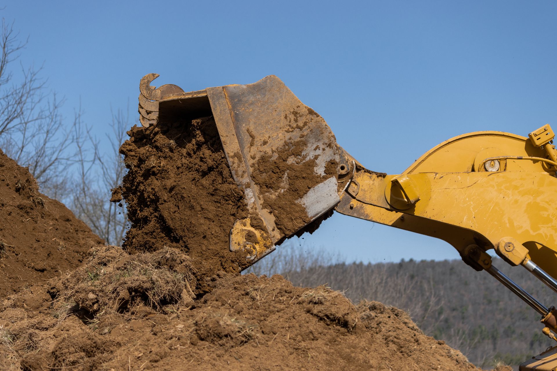 A bulldozer is scooping dirt from a pile of dirt.