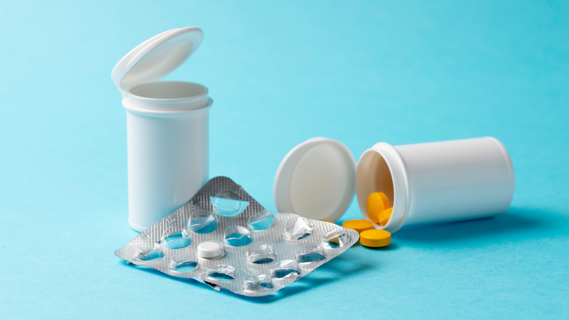 A bottle of pills and a blister pack of pills on a blue background.