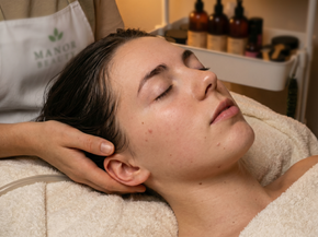 Woman receiving a facial massage while reclining on a towel-covered treatment bed