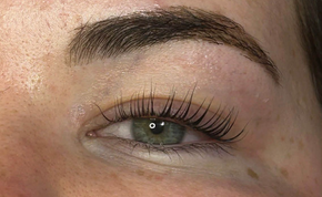 Close-up of one eye with long curled eyelashes and well-groomed eyebrow