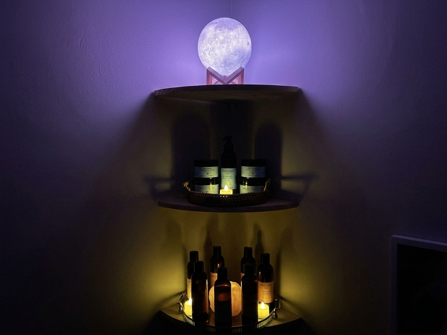 Wall-mounted two-tier shelf with glowing bottles and a crystal orb, lit in purple and amber light.