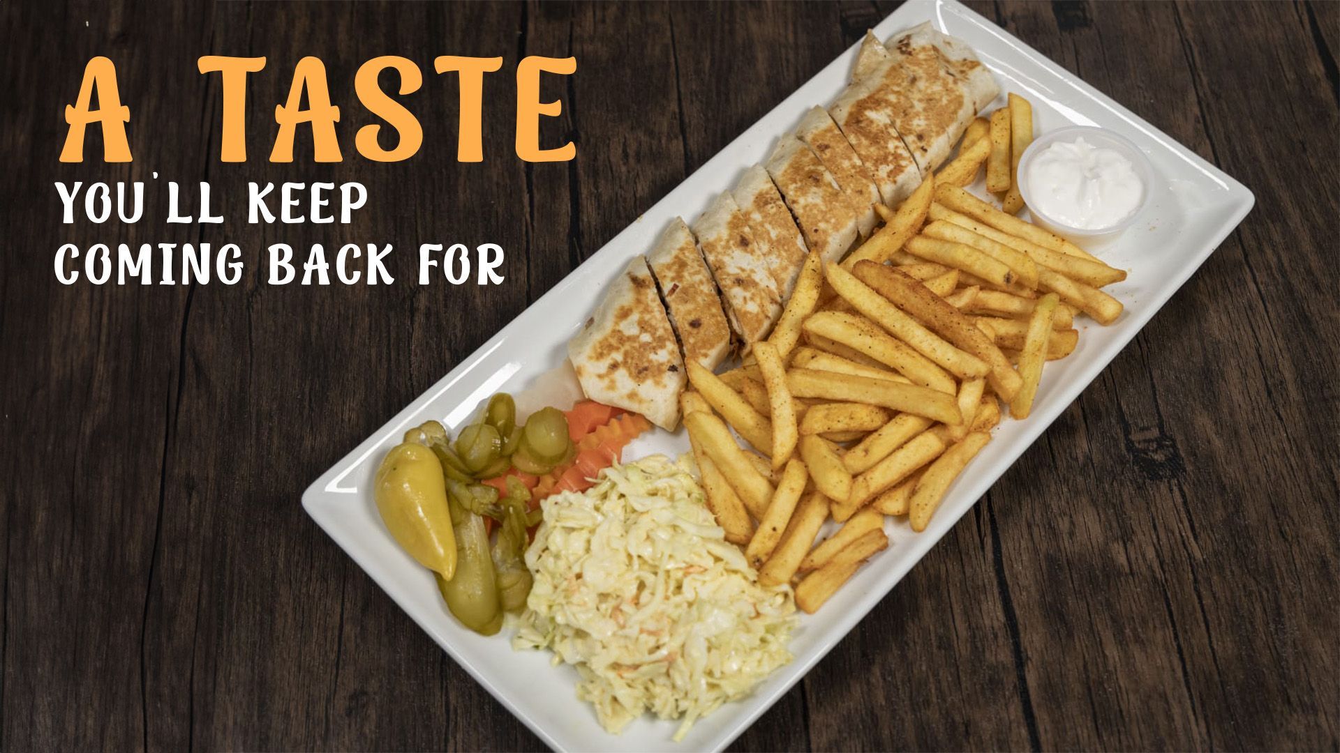 A white plate topped with french fries and a sandwich on a wooden table.