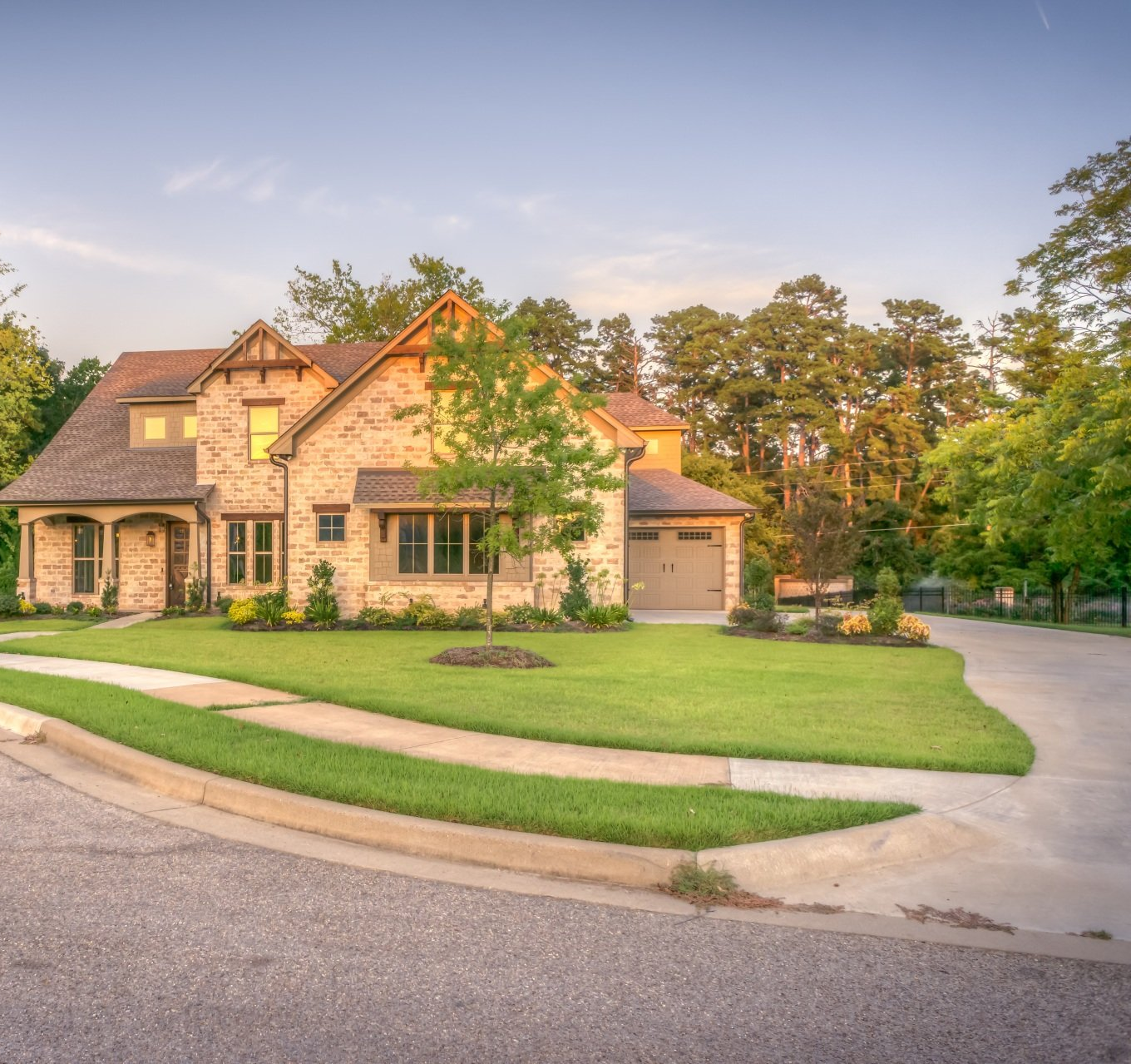 Beige brick home with a landscaped yard and a curving driveway.