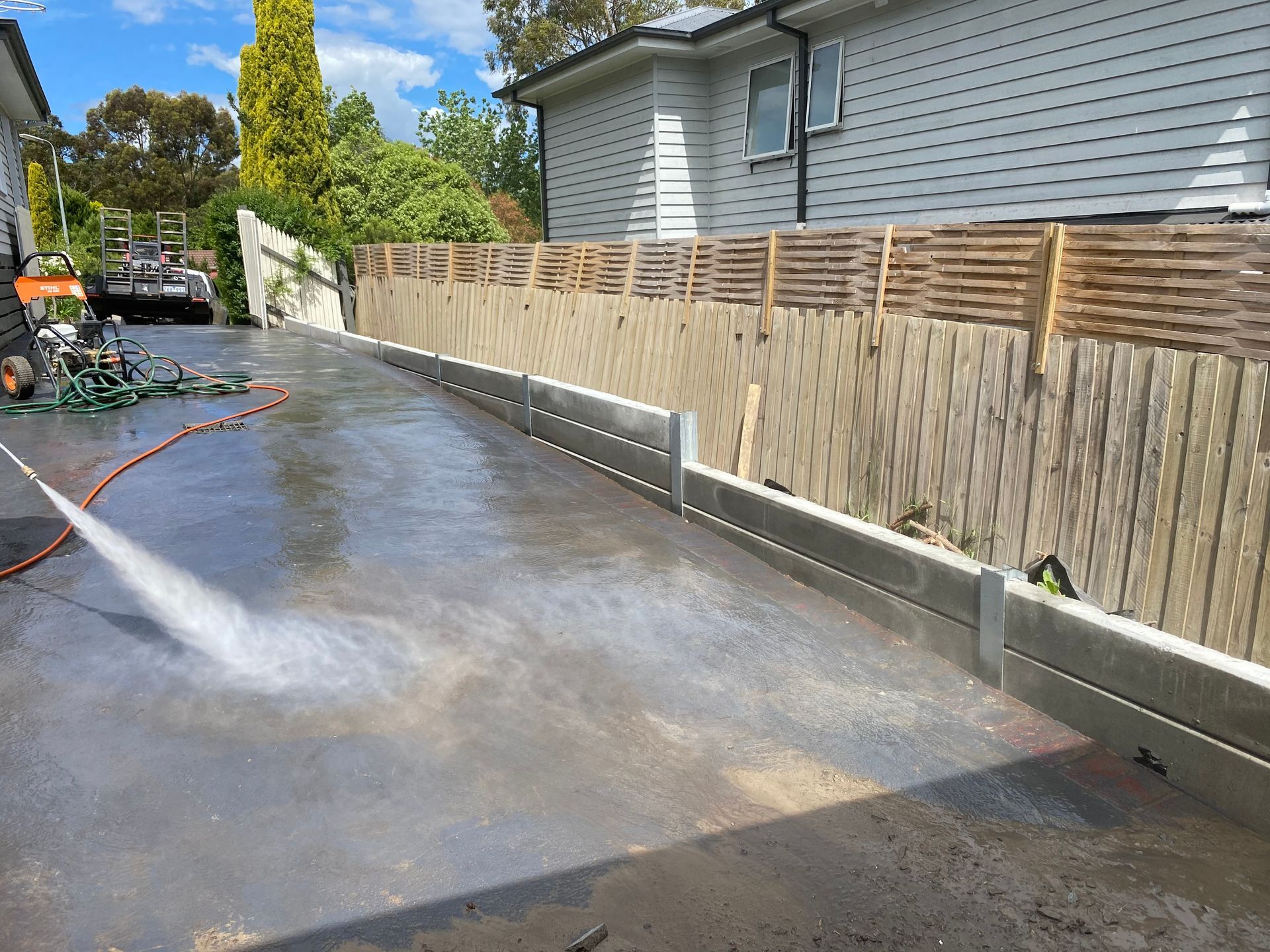 A stone wall surrounds a lush green yard in front of a house.