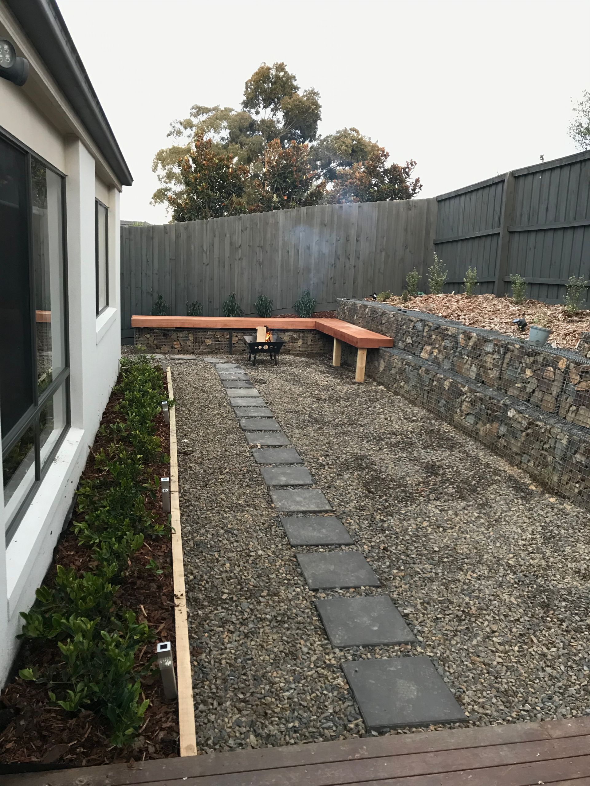 A house with a lot of bushes and trees in front of it