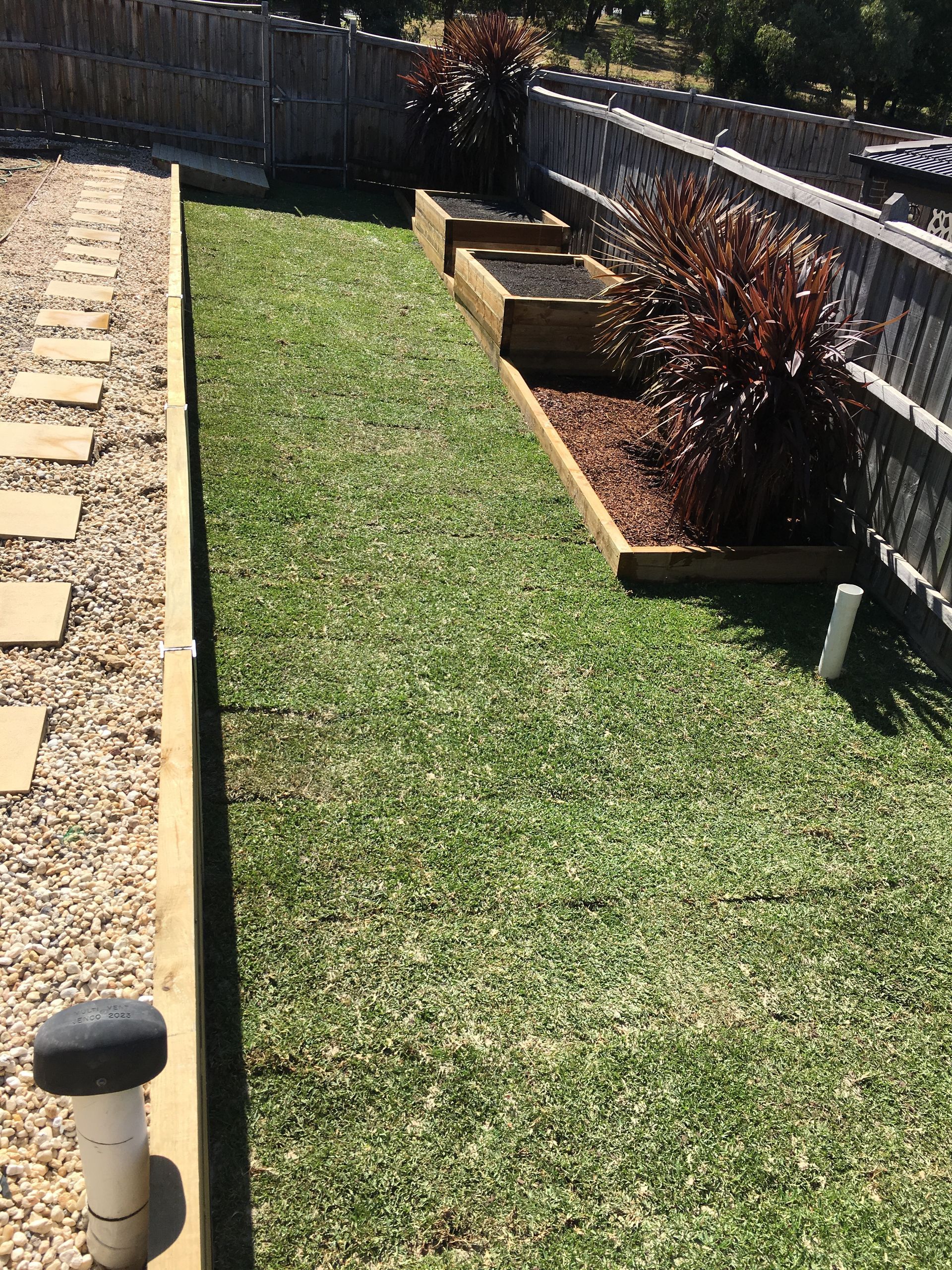 A large lush green lawn with a wooden fence in the background.