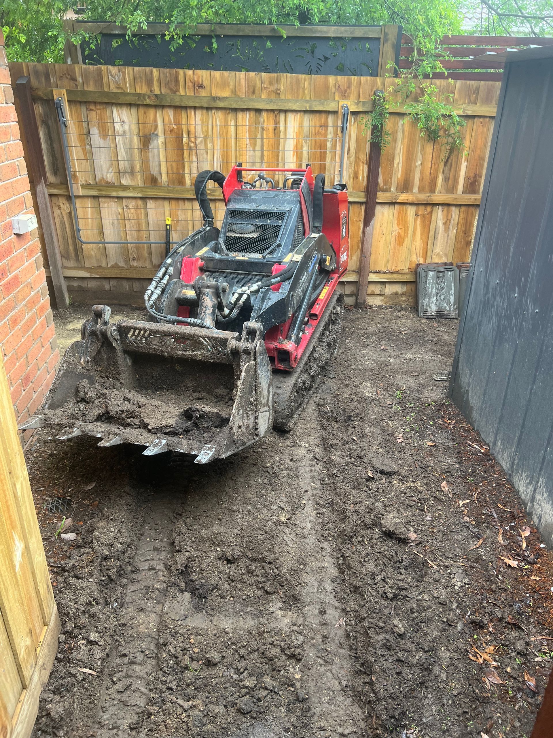 A backyard with a fence and a driveway being built.