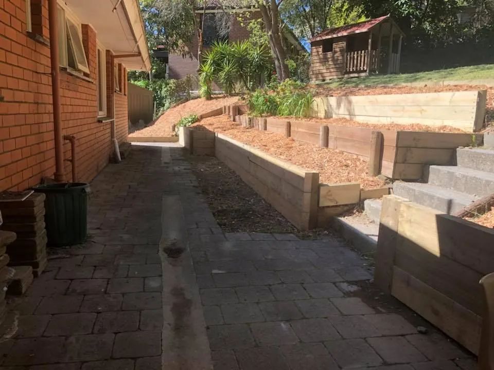 A brick walkway leading to a house with a truck parked on the side of it.