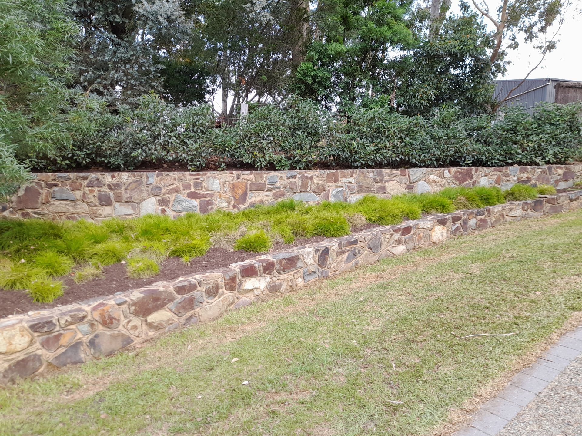 A row of wooden planters filled with flowers next to a brick wall.