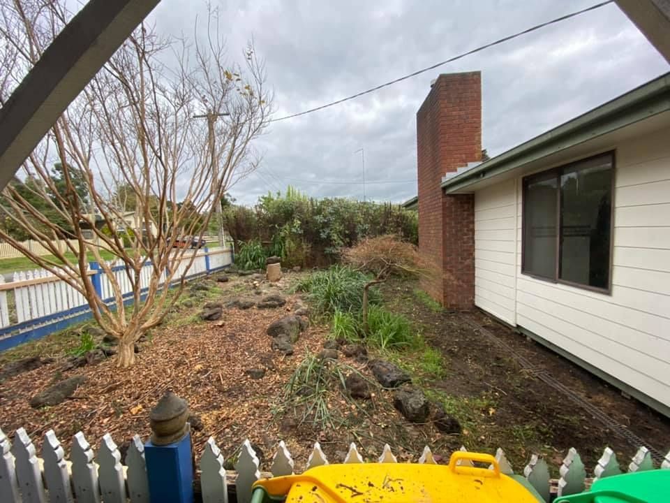 A yellow trash can is sitting in front of a house.