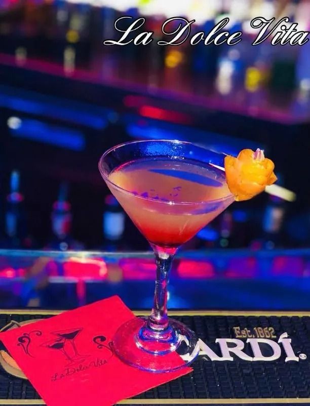 Cocktail in bicchiere da Martini guarnito con agrumi su un bancone, menù rosso, scritta 