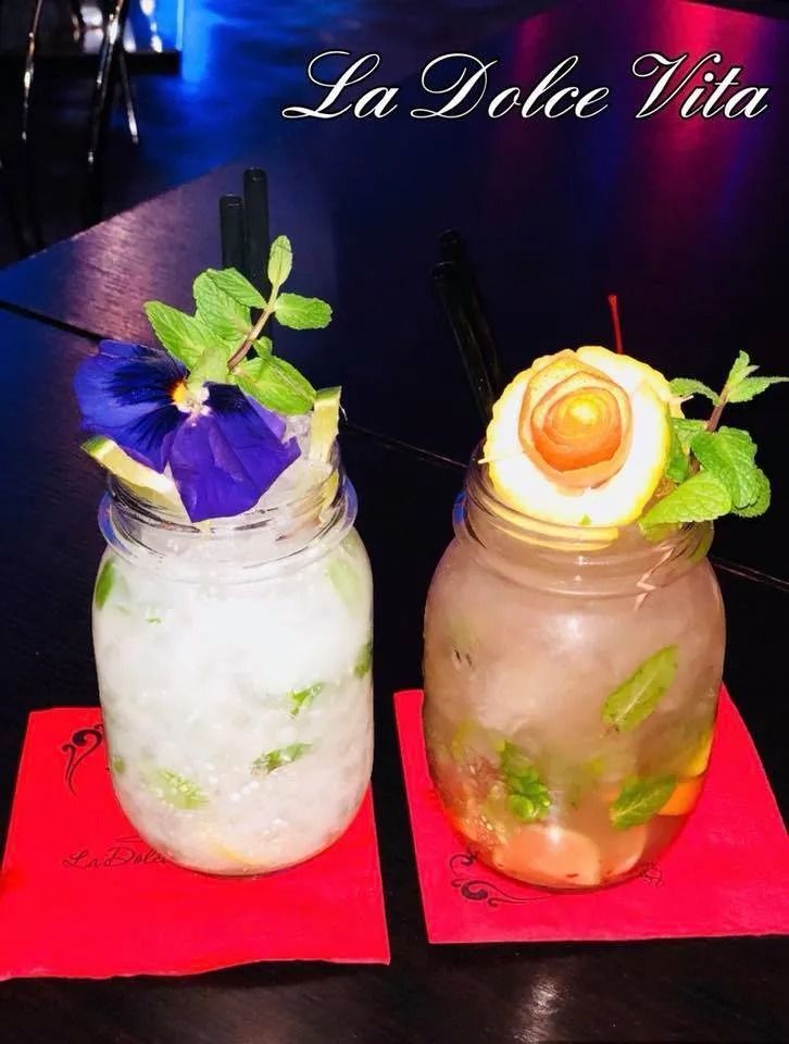 Due cocktail in barattoli di vetro con guarnizioni su sottobicchieri rossi.