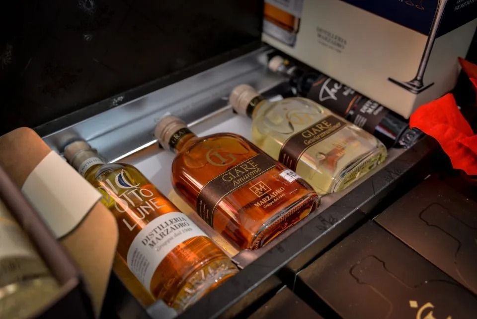 Bottiglie di liquore, per lo più ambrate, esposte su uno scaffale metallico.