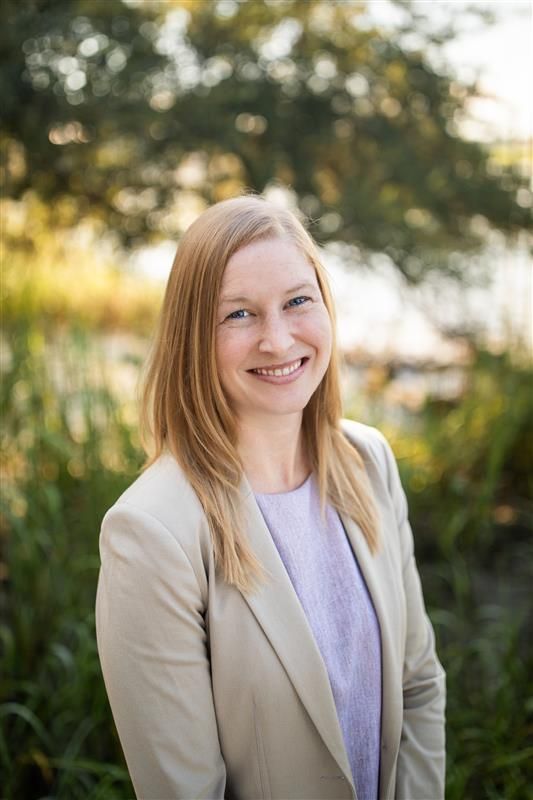 A woman with blonde hair and freckles is smiling for the camera.