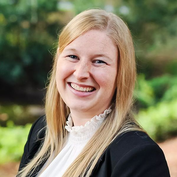 A woman with blonde hair and freckles is smiling for the camera.