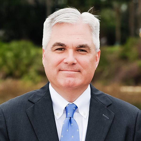 A man in a suit and tie is smiling for the camera